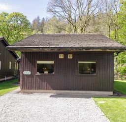 A wooden cabin with windows and a gravel path at Dogwood Timber Lodge in Keswick