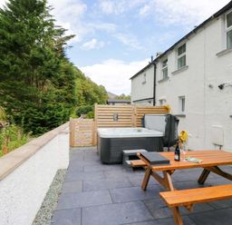 An outdoor area with a hot tub and wooden table at Riverside Cottage No 4 in Keswick