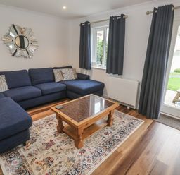 A living room with a blue sofa and coffee table at Chellowdene Cottage in Falmouth