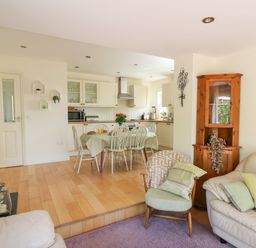 An open plan living area with a kitchen dining table and chairs a wooden cabinet and armchairs at Lavender Lodge in Haverfordwest