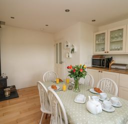 A kitchen dining area with a table set with cups croissants and orange juice at Lavender Lodge in Haverfordwest