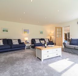 A living room with blue and gray sofas a wooden coffee table and framed pictures on the wall at Little Chapter in Walberswick