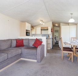 A living area with a gray sectional sofa with red pillows an open kitchen and a dining table with chairs at Swinside in Lorton