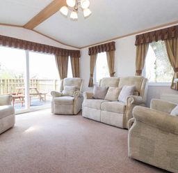 A living room with beige sofas and armchairs near large windows with brown curtains at Whiteside in Lorton