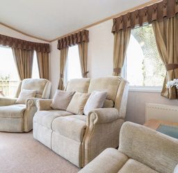 A sitting room with beige sofas and armchairs next to windows with brown curtains and a small table with a plant at Whiteside in Lorton