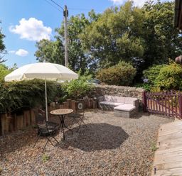 A garden with a table and chairs under an umbrella at Coach House Haverfordwest near Broad Haven