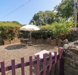 A garden with a table and chairs under an umbrella at Coach House Haverfordwest near Broad Haven