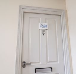 A closed white door with number 15 and a small sign with birds above the number at Kittiwakes The Bay - Filey