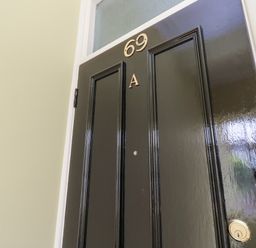 A black door with the numbers 69 and letter A on it at Chine Heights in Bournemouth