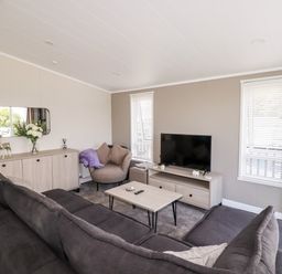 A living room with gray sofas a coffee table and a TV on a stand at 63 The Maples in Hewas Water near Sticker