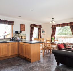 A kitchen and dining area with wooden cabinets dining table and sofa at Lovat Highland Bothy in Beauly