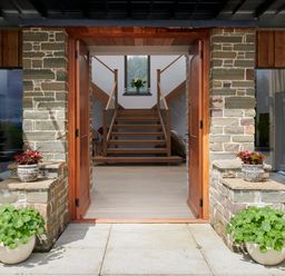 An entrance with open wooden doors stone walls potted plants and stairs inside at Ben Luna Lodge in Drumnadrochit Loch Ness