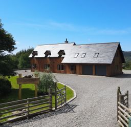 A wooden lodge with a gravel driveway and wooden gates at Ben Luna Lodge in Drumnadrochit Loch Ness