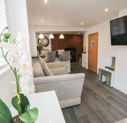 A living room with a couch a mounted television and a dining area with chairs at Tower Apartment in Whitby
