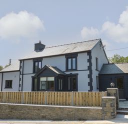 A two story house with black and white exterior and a wooden fence in front at Rhiwmynach in Pontarfynach near Aberystwyth