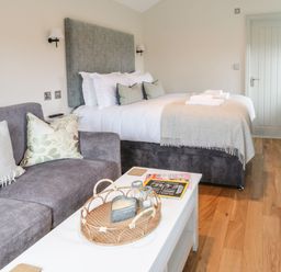 A bedroom with a double bed and a grey sofa with cushions at The Folly in Linton near Thresfield