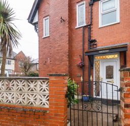 The entrance to a brick house with a white door and metal gate at South Bay Beach House in Bridlington