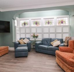 A living room with blue leather sofas orange patterned armchair and shuttered windows at South Bay Beach House in Bridlington
