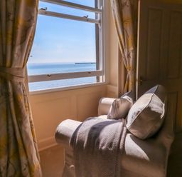A sitting room with a chair and window at 123 On The Sea – Victoria’s Place Weymouth