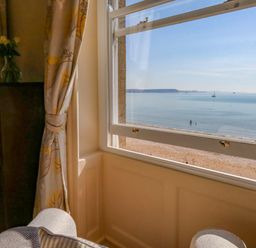 A view of the beach and sea from a window at 123 On The Sea – Victoria’s Place in Weymouth