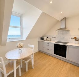 A kitchen with a table and chairs at 123 On The Sea – The Eaves, Weymouth