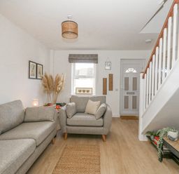 A living room with two grey sofas a window and a front door near stairs at The Nightingale in Weymouth