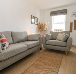 A living room with two grey sofas a window and wall art at The Nightingale in Weymouth