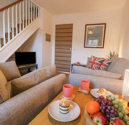 A living room with two sofas a wooden table with fruit and snacks and a lamp at The Nightingale in Weymouth