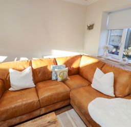A living room with a brown sofa and cushions at Nene's Nest in Alnwick