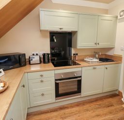A kitchen with basic appliances and cabinets at Nene's Nest in Alnwick