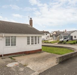 A white detached house with a driveway and a curved brick wall at 31 Sisial Y Mor in Rhosneigr