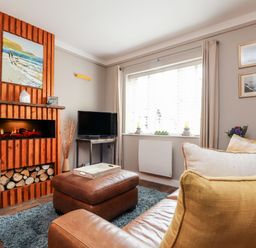 A living room with a fireplace painting tv leather furniture and a window at Inny Brook Cottage Davidstow near Camelford