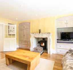 A living room with a wooden coffee table fireplace and a television at The Farmhouse in Felmingham near North Walsham