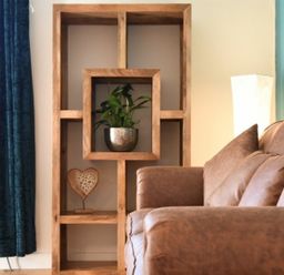 A wooden shelf with a plant and a heart decoration beside a brown sofa and a floor lamp in a living room at The Loft (Amble) in Amble