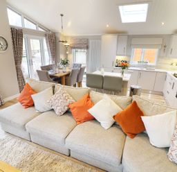 An open plan living room and kitchen with a beige sofa and dining table at 8 Waterside Wood White Cross Bay near Troutbeck Bridge