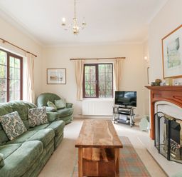 A living room with green sofas a wooden coffee table a fireplace and a television at Brantfell Lodge in Bowness-On-Windermere