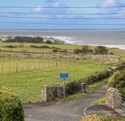 A coastal view with fields and a roadway at Tawelfan in Llwyngwril