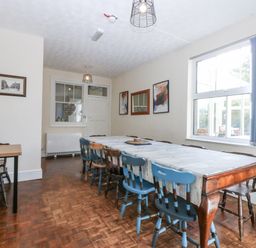 A dining room with a long table and blue chairs at Tawelfan in Llwyngwril