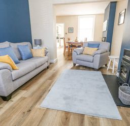 A living room with gray sofas yellow and blue cushions a fireplace and a blue rug at Leos Place in Weymouth