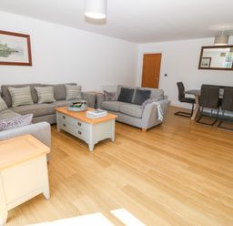 A living room with two grey sofas a coffee table side tables a dining table with chairs and framed pictures on the wall at 3 Pensyflog Barns in Porthmadog