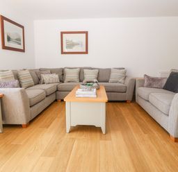 A living room with two grey sofas a wooden coffee table and framed pictures on the wall at 3 Pensyflog Barns in Porthmadog