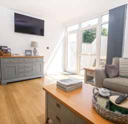 A living room with a sofa coffee table and cabinet with television at 3 Pensyflog Barns in Porthmadog