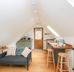 A small kitchen and living area with a wooden door and sloped ceiling at The Rookery in Fulbrook near Burford