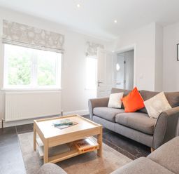 A living room with gray sofas and a wooden coffee table with books and a game at 1 Millbank in Keswick