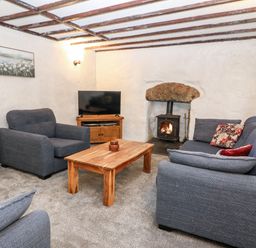 A living room with a wooden coffee table blue sofas a television and a fireplace at Is Y Graig in Beddgelert