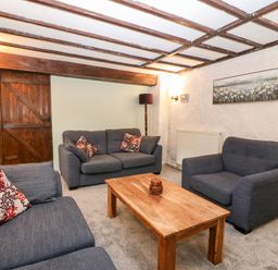 A living room with three sofas a wooden coffee table and a wooden door at Is Y Graig in Beddgelert