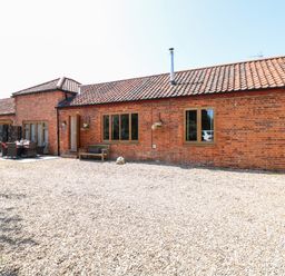 A brick building with tiled roof and gravel ground with outdoor seating at The Barnhouse Felmingham near North Walsham