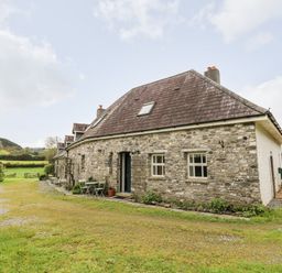 Stone cottage with small tables and chairs outside in grassy area at Heron House in Talley near Llandeilo