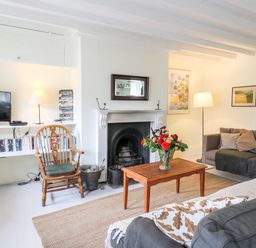 A living room with a fireplace a wooden chair and a television on a shelf at Buzzards Watch in Talley near Llandeilo