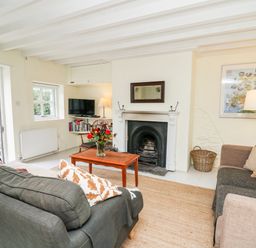 A living room with two sofas a wooden coffee table a fireplace and a television at Buzzards Watch in Talley near Llandeilo